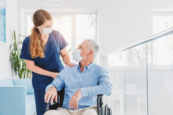 female care giver with eldery male patient in wheelchair